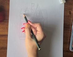 a person holding a pencil in their left hand and drawing on paper with colored crayons