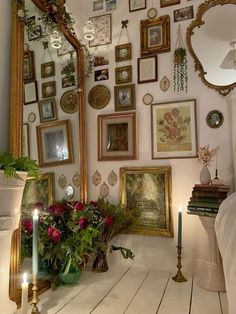 a room filled with lots of framed pictures on the wall next to a candle and flowers