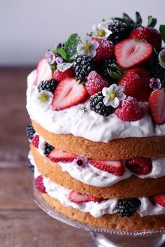 a layered cake with strawberries and blackberries on top