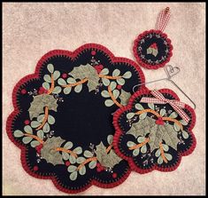 two black and red placemats with holly decorations