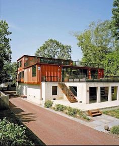 a house made out of shipping containers with stairs leading up to the second floor and upper level