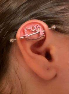 a girl with pink ear piercings that has the word love written on it and is wearing an ear pin