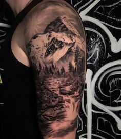 a man with a mountain and river tattoo on his arm