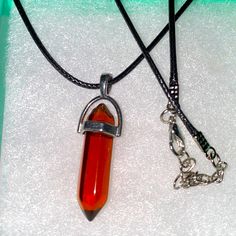 a necklace with a red glass pendant on a black leather cord and a silver chain