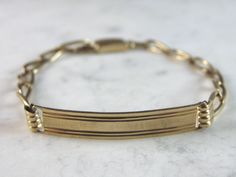 "A MENS VINTAGE ESTATE 14K YELLOW GOLD CHAIN ID BRACELET. THE BRACELET MEASURES 8 5/8\" LONG BY 1/4\" AND WEIGHS 9.9g. THE ID BAR MEASURES 1 5/8\" BY 1/4\". BRACELET IS MARKED 14K. ANY QUESTIONS, PLEASE CALL. THIS MAKES A GREAT GIFT FOR THAT SOMEONE SPECIAL. BE SURE TO CHECK OUT SOME OF OUR OTHER GREAT ITEMS FOR SALE." Classic Gold Bracelet In Brass, Classic Gold Brass Bracelet, Tarnish Resistant, Antique Yellow Gold Link Bracelet, Classic Gold Brass Bracelet Tarnish Resistant, Classic Tarnish Resistant Gold Brass Bracelet, Classic Tarnish-resistant Gold Brass Bracelet, Yellow Gold Link Bracelet In Brass, Formal Yellow Gold Brass Bracelets, Classic Yellow Gold Brass Bracelet