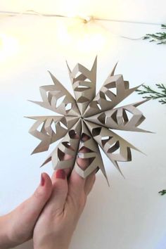 someone is holding a paper snowflake in their hand and it looks like they are going to fall