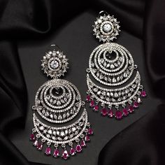 Beautiful American Diamond Chand Bali Earrings with Ruby Red Stones in Silver Finish that are perfect for party wear! Fluttery crystals add just the right amount of sparkle and shine to this delicate pair! Elegant in its simplicity, these heirloom-quality earrings are anchored with numerous american diamond zircon stones. Approximate earrings length is 3.5″. Designed over high-quality brass as base metal. Party Chandbali Earrings With Cubic Zirconia, Ruby Drop Earrings For Party, Ruby Chandelier Drop Earrings For Party, Ruby Drop Earrings For Bridal Party, Party Ruby Earrings In Silver, Red Round Earrings With Sparkling Stones, Festive Cubic Zirconia Chandelier Earrings For Party, Ruby Bridal Earrings For Party, Festive Party Chandelier Earrings In Cubic Zirconia