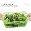 a green basket filled with lettuce on top of a white table next to two hands