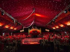 an indoor event with red lighting and checkerboard flooring on the dance floor