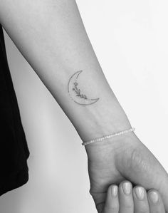 a woman's arm with a small crescent tattoo on the left inner forearm and wrist