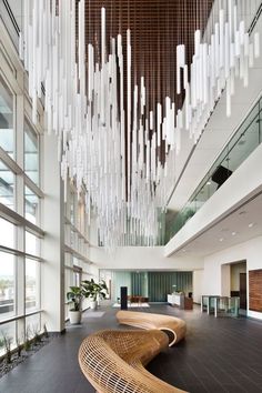 an empty lobby with wooden benches and chandelier hanging from it's ceiling