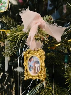 an ornament hanging from the top of a christmas tree with ribbons on it