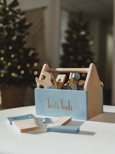 a wooden tool box with tools in it sitting on a table next to a christmas tree