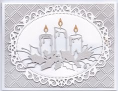 a white card with two candles on it and some leaves in the middle, surrounded by intricate filigrees