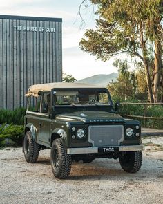 an army green jeep parked in front of a building