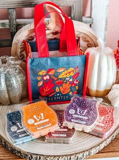 four different colored bags sitting on top of a wooden table next to pumpkins and other decorations