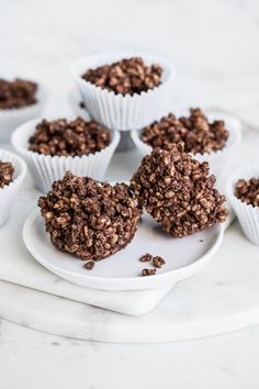 chocolate cupcakes on a white plate surrounded by other muffins