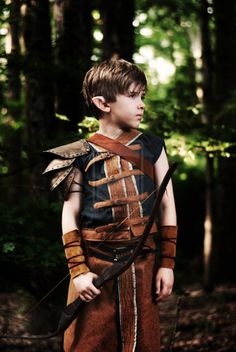 a young boy dressed up as a warrior in the woods