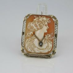 Antique 14K White Gold Rectangular Pin Pendant Deco, shell cameo with round diamond necklace, woman looking right, 1 1/2 x 1 1/4 inch, filigree frame with applied leaf corners, Circa 1925, locking clasp, hinged bail, 11 grams. Stock # BB266CamPP15 This listing contains photographs of the actual item you will receive. Our items are in excellent condition with little or no signs of wear and many are one of a kind pre-owned estate finds. Please look closely at the pictures in this listing as they a Antique Engraved Necklace With Rectangular Pendant, Antique Rectangular Locket Necklace, Antique Pendant Brooches Hallmarked, Antique Gold Intaglio Brooches, Collectible Cameo Pendant Brooches, Pin Pendant, Round Diamonds, Diamond Necklace, Perfume Bottles