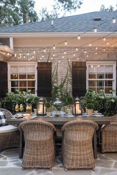 an outdoor dining area with wicker chairs and lights