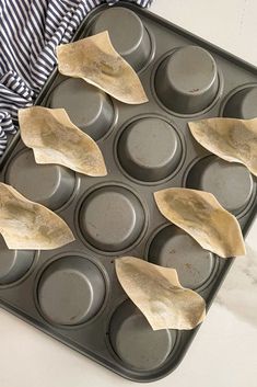 some tortilla wrappers in a muffin tin on top of a table