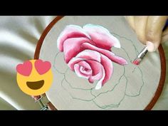 someone is drawing a rose on a piece of fabric