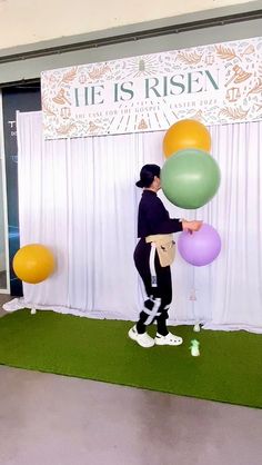 a man standing on top of a green carpet next to a wall with balloons in it