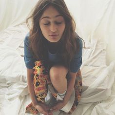 a young woman sitting on top of a bed holding a stuffed animal in her hands