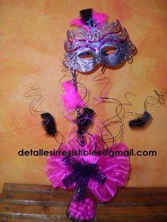 a purple and black mask on top of a wooden table next to a pink flower