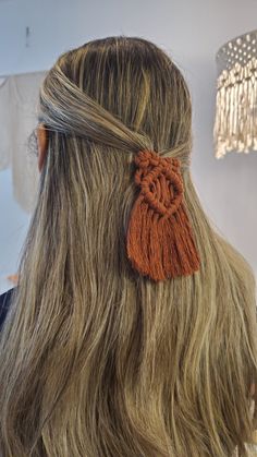 the back of a woman's head with long blonde hair and an orange tassel