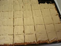 a pan filled with white frosted squares of cake on top of a stovetop