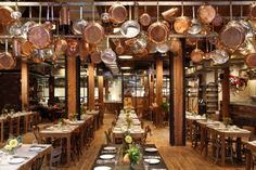 a restaurant with wooden tables and hanging pans