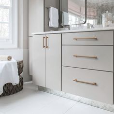 a bathroom with marble counter tops and gold handles on the cabinet doors, along with white towels