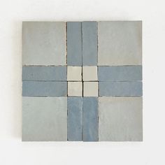 four square blue and white tiles on a white surface, with one block missing from the center