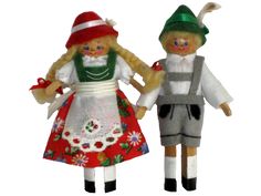 two dolls are dressed in colorful clothing and hats, one is holding the other's hand