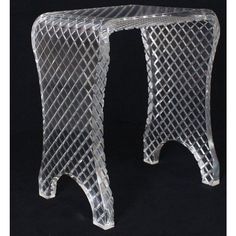 two clear glass stools sitting side by side on a black background with the legs bent down