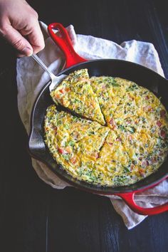 an omelet in a skillet with a red spatula on the side