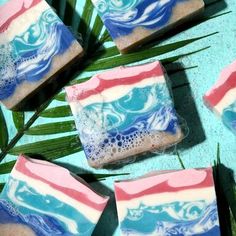 soap bars with blue, pink and white swirled designs on them next to palm leaves