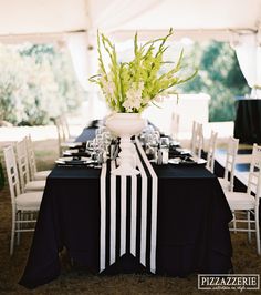 a black and white table setting with flowers in a vase on the centerpieces