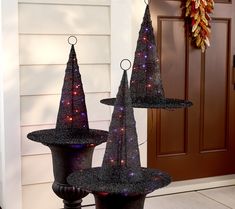 three black witches hats on top of each other in front of a door with lights