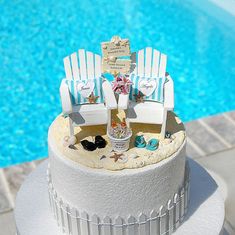 a cake that is sitting on top of a table next to a pool with chairs