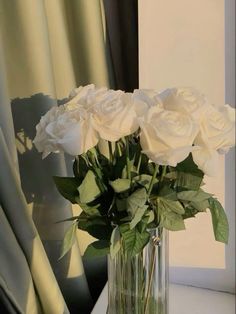 a vase filled with white roses on top of a table