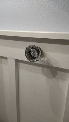 a door handle on the side of a white door with a silver flower in it