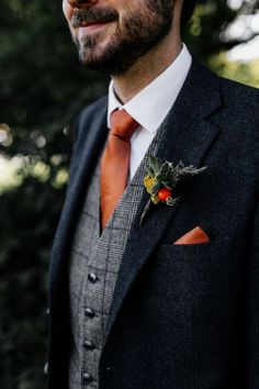 a man wearing a suit and tie with a flower in his lapel pocket, smiling at the camera