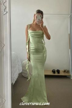 a woman is taking a selfie in a mirror wearing a green dress and holding a cell phone