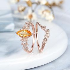 two gold rings with an orange topazte and diamonds