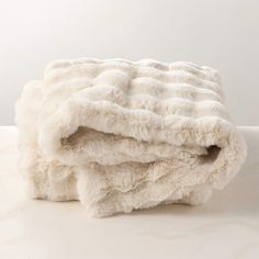 two blankets folded on top of each other in front of a white wall and floor