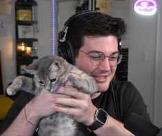 a man wearing headphones holding a kitten