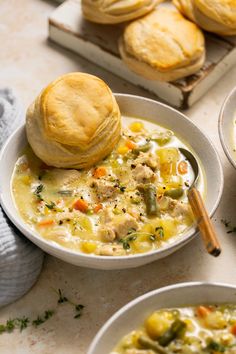 two bowls of soup with biscuits on the side and one bowl filled with chicken pot pies