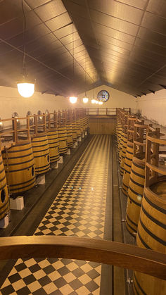 rows of wooden barrels lined up in a room with black and white checkered flooring